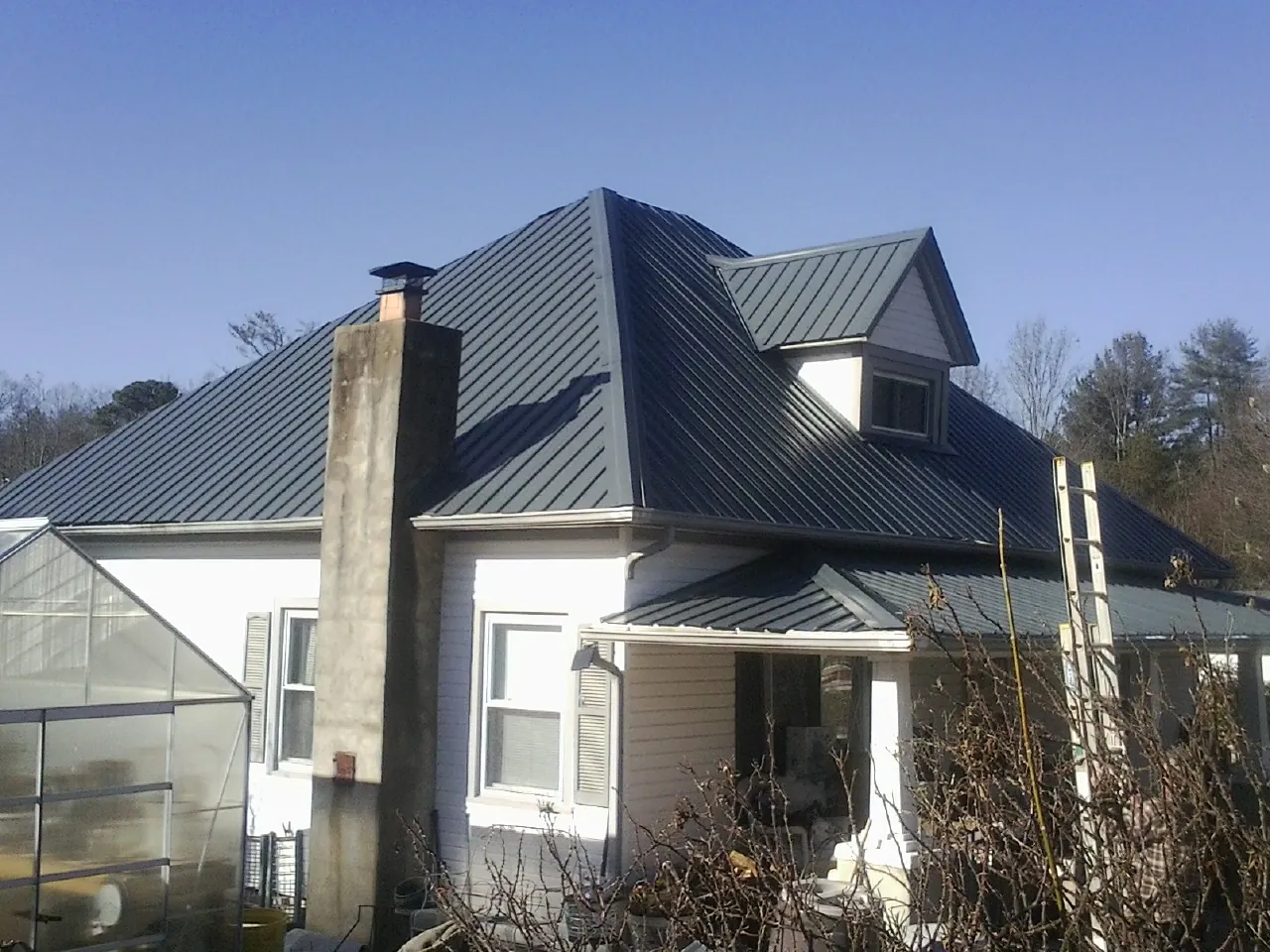 Dark blue standing seam metal roof on a white farmhouse with dormer — Slate & Tile Roof Repair by Roofing Brothers in Perham