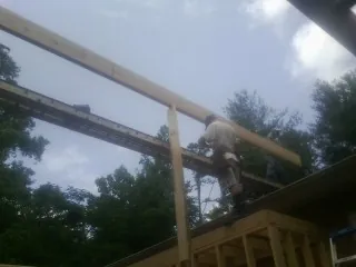 Carpenter setting a ridge beam over a new addition frame — Ice Dam Removal by Roofing Brothers in Perham