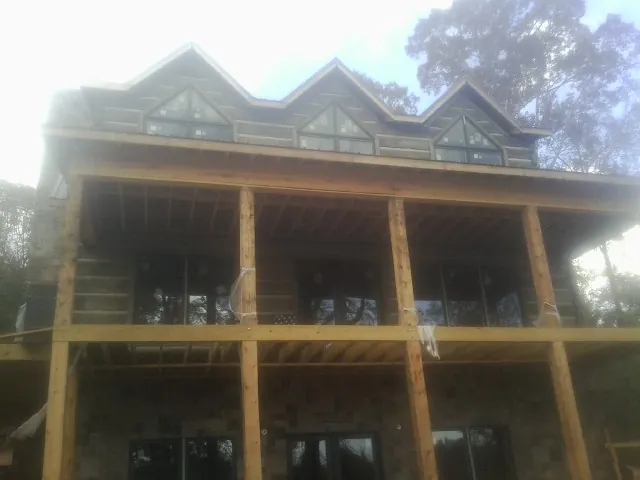 Dormers and porch framing on a large log home under construction — Roof Coating work by our crew in Perham