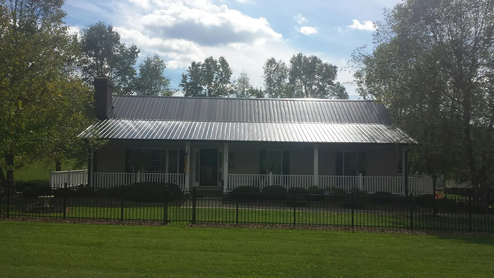 Gray metal roof on a brick ranch with a full width front porch — Gutter Guard Installation work by our crew in Perham